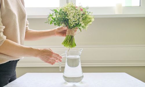 woman-hands-with-bouquet-flowers-vase-table